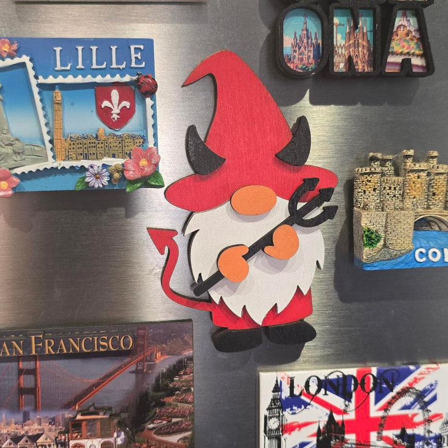 Collection of magnets on a metallic surface, including a gnome, flags, and cityscape designs.