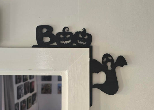 Decorative Halloween mirror with black cut-out designs on a white wall.