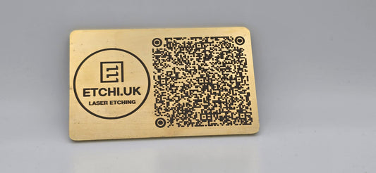 Gold metal card with laser engraved QR code and branding on a gray background