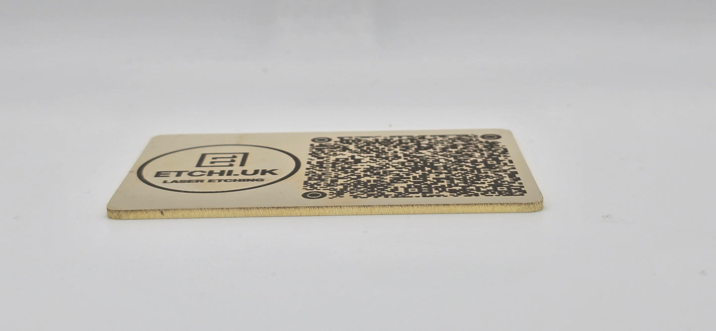 Rectangular brass business card with QR code and text on a white background
